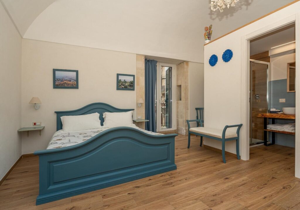 Camera Ciarciolo: letto blu, comò e luce dalla finestra